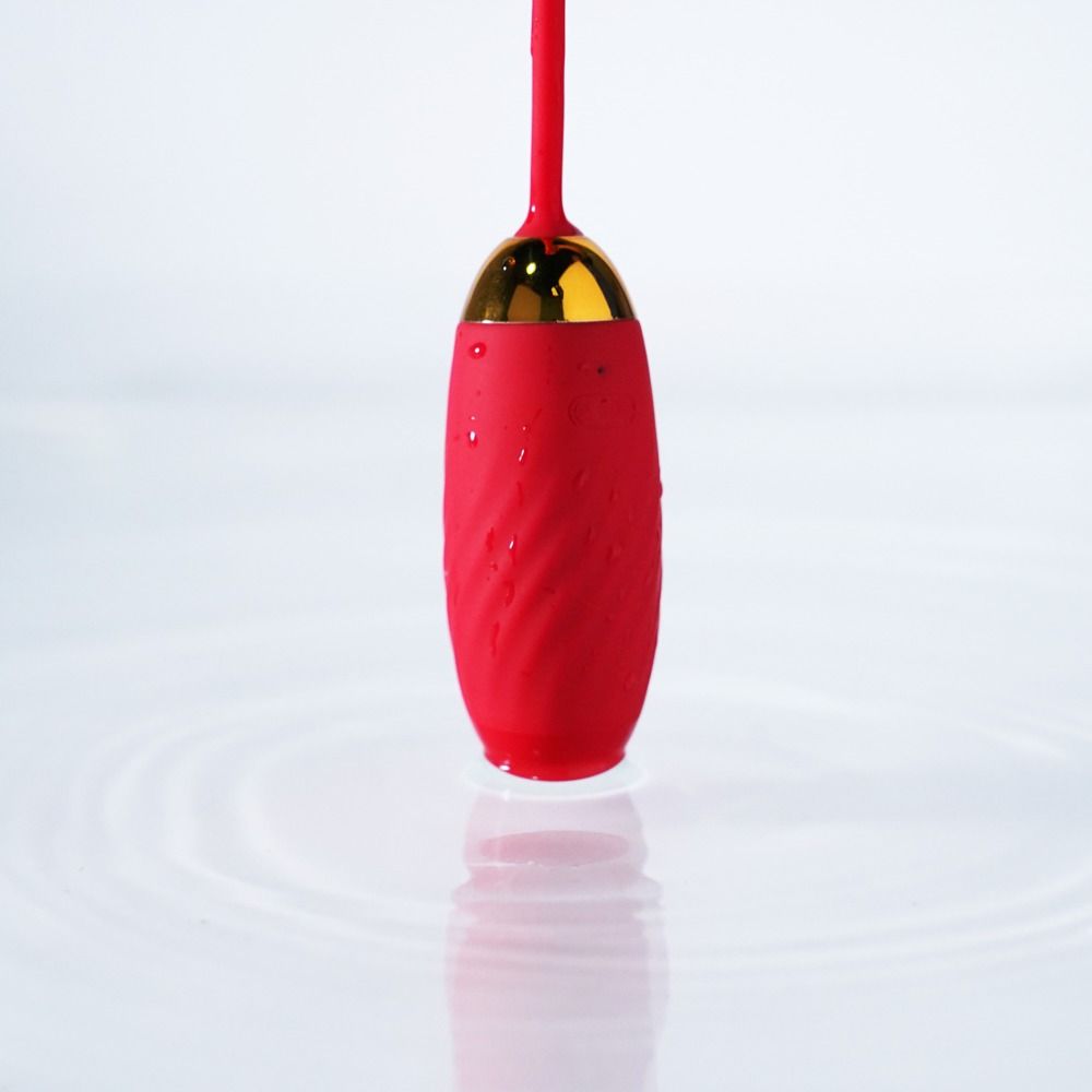 Balle vibrante rouge avec accent doré, mouillée et sur l'eau.