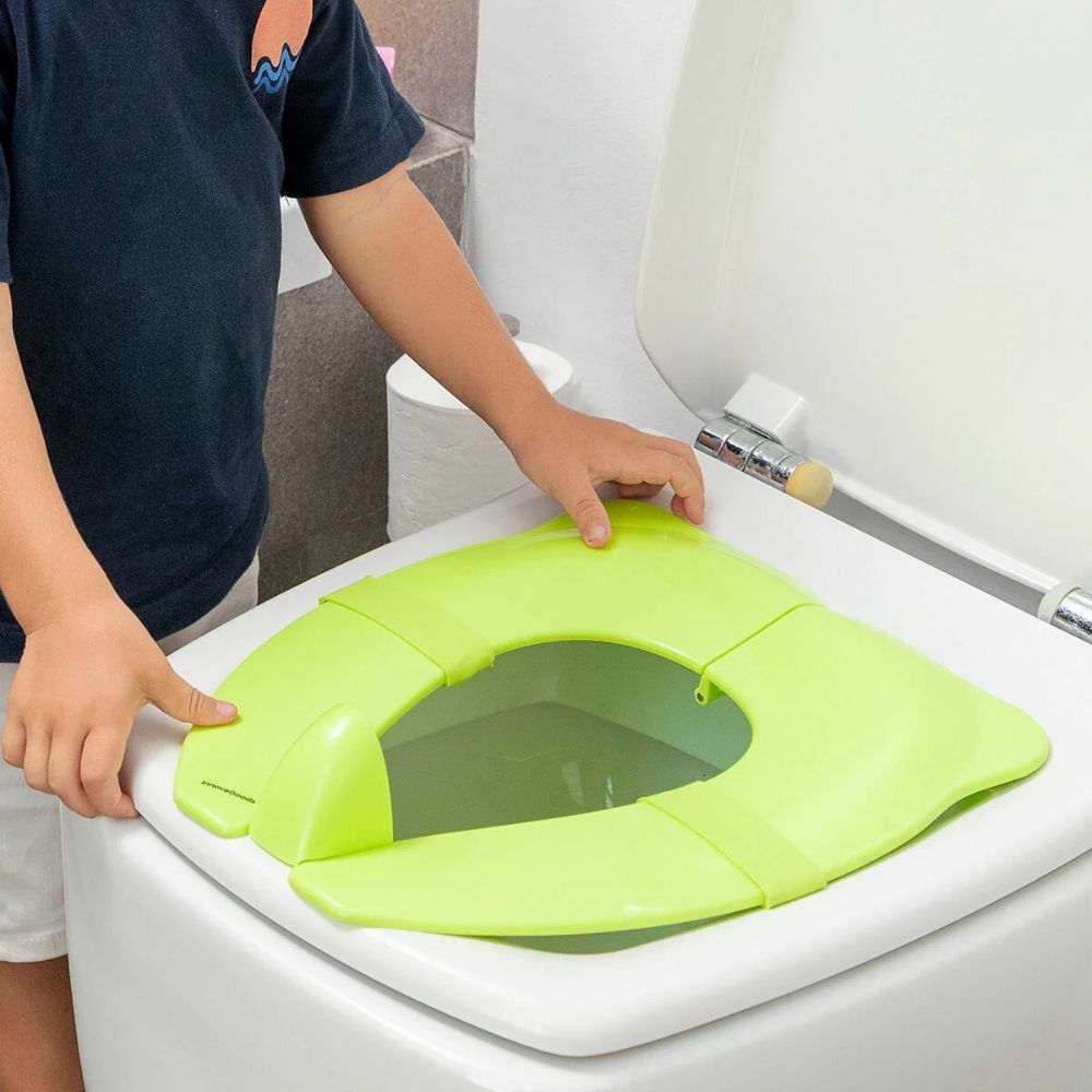 Groene toiletverkleiner voor kinderen op een toilet. Kind plaatst de zitting. Merk InnovaGoods.