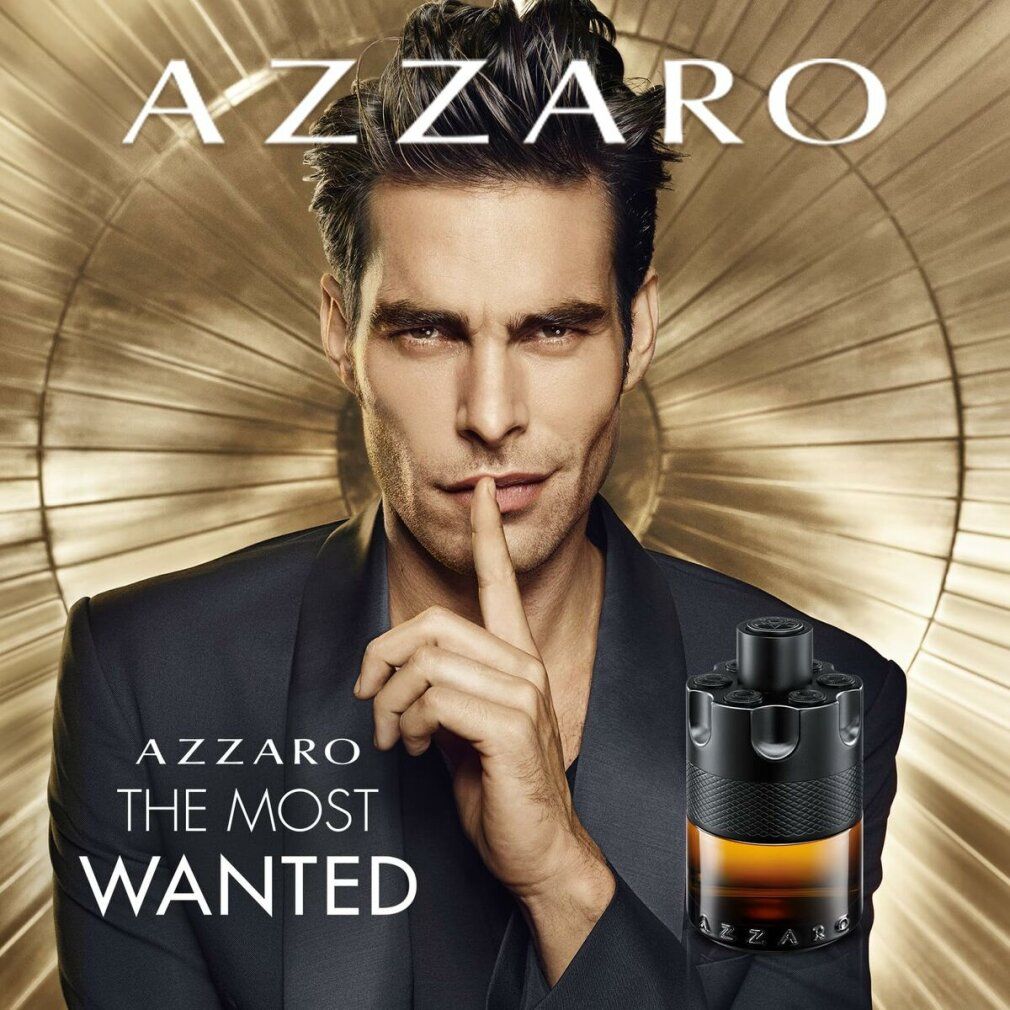 Man met Azzaro The Most Wanted Parfum. Zwart pak, vinger op de lippen. Gouden achtergrond.