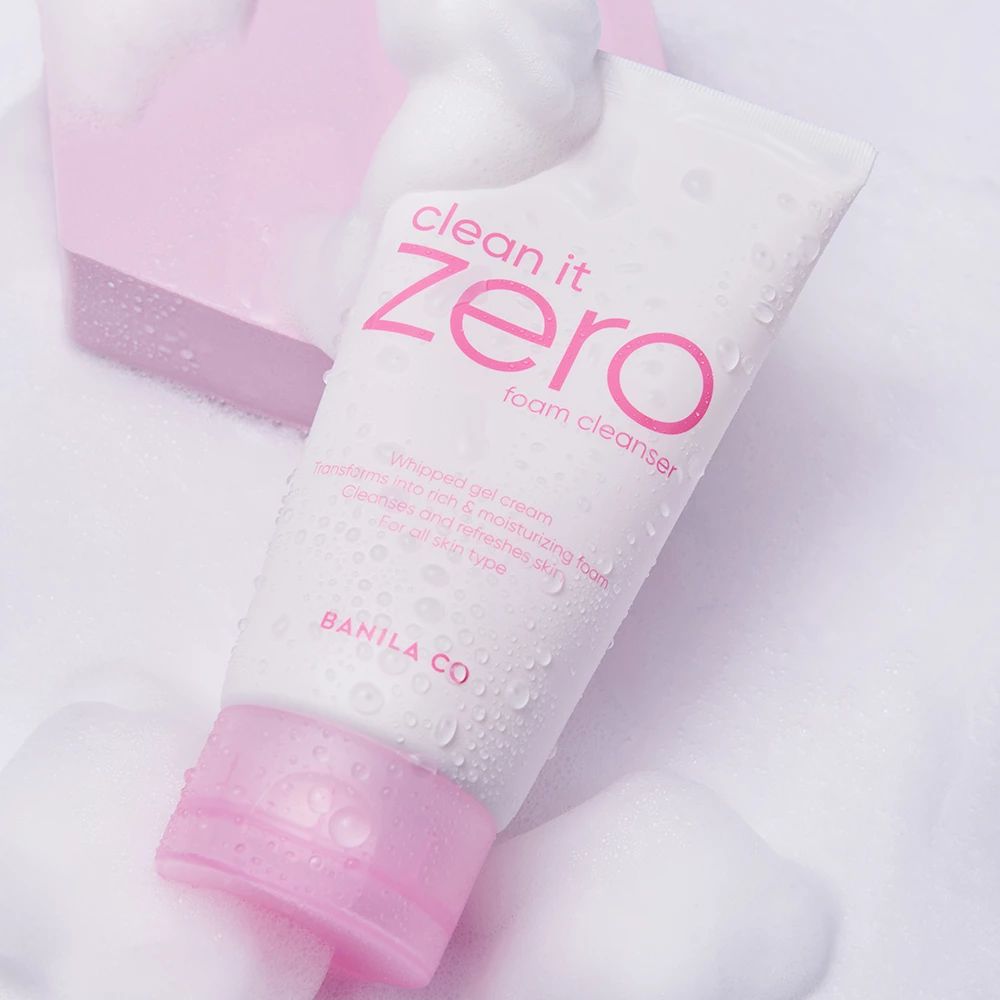 Tube blanc avec détails roses et texte "clean it zero foam cleanser". Entouré de mousse. Logo BANILA CO.
