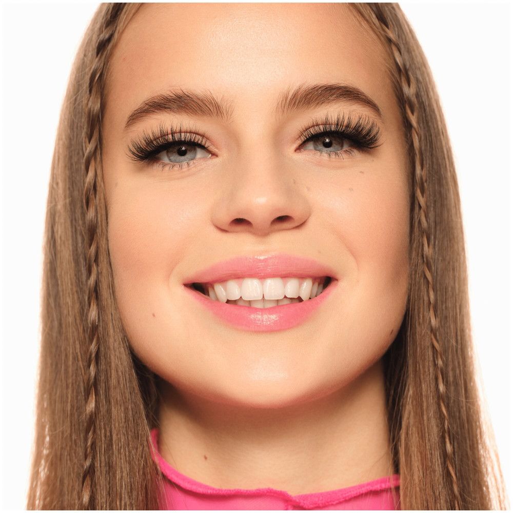 Portrait d'une femme avec de longs faux cils noirs. Elle sourit.