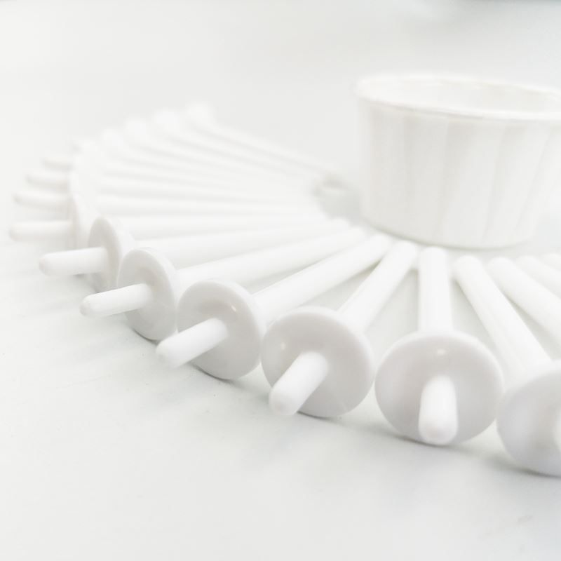 Plusieurs applicateurs de cire nasale blancs sont disposés en cercle autour d'une petite tasse blanche.