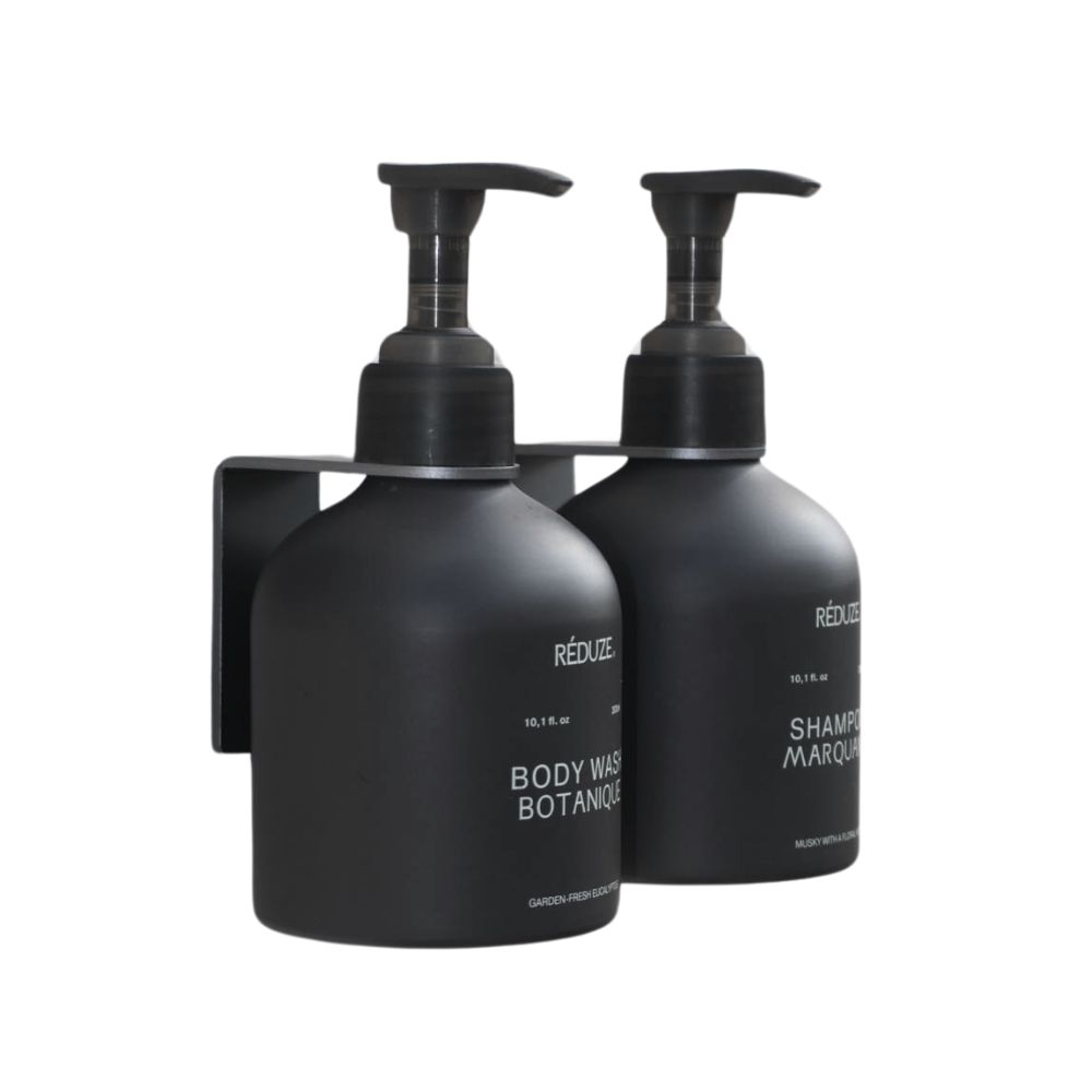 Deux flacons noirs avec supports muraux. Inscription : RÉDUZE, Body Wash Botanique, Shampoo Marquant.