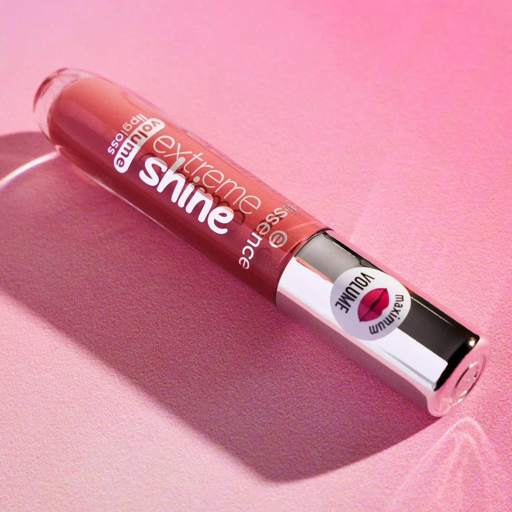 Lipgloss tube met zilveren dop. Opschrift: Extreme Shine, Volume Lipgloss. Op de dop: sticker met lippensymbool en Volume. Op roze achtergrond.