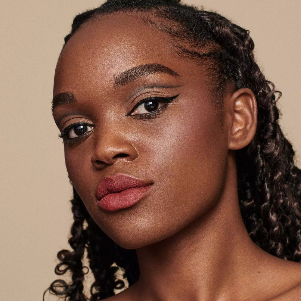 Portret van een vrouw met een donkere huid. Lippenstift op de lippen. Kijkt in de camera.