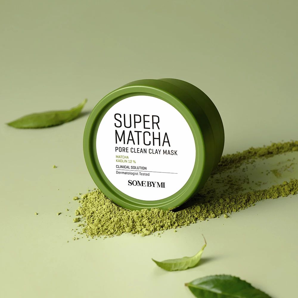 Groene container met deksel. Opschrift: Super Matcha Pore Clean Clay Mask. Groene theebladeren en poeder.