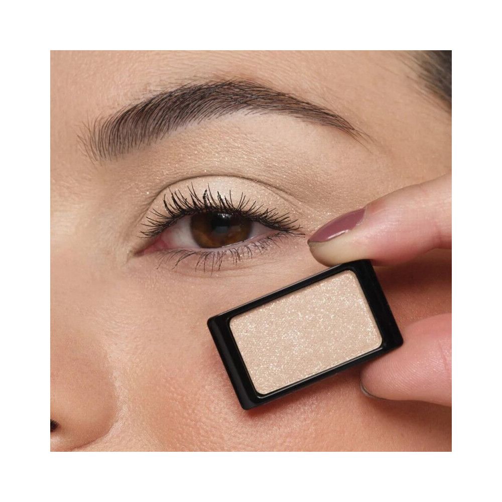 Oog met oogschaduw. Een rechthoekige, beige oogschaduw wordt voor het oog gehouden. Zwart kader.