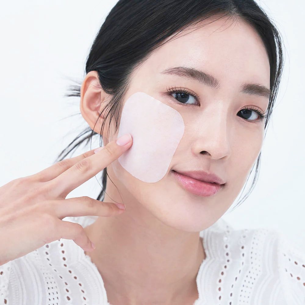 Femme avec un tampon sur la joue. Le tampon est carré et rose. La femme porte un haut blanc.