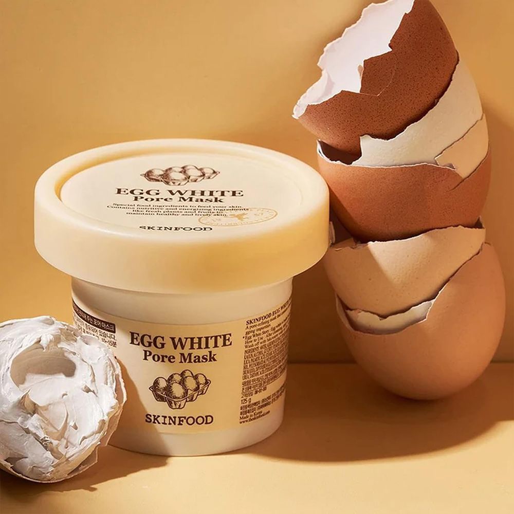 Pot avec masque, coquilles d'œufs à côté. Texte: Egg White Pore Mask, Skinfood.
