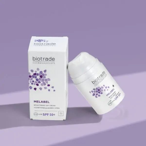 Witte Biotrade Melabel dagcrème met verpakking. Opschrift: Melabel Brightening Day Cream SPF 50+. Paars logo en tekst.