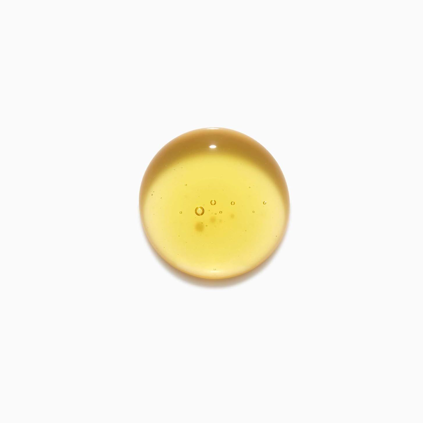 Druppel gouden shampoo vloeistof met belletjes op witte achtergrond.