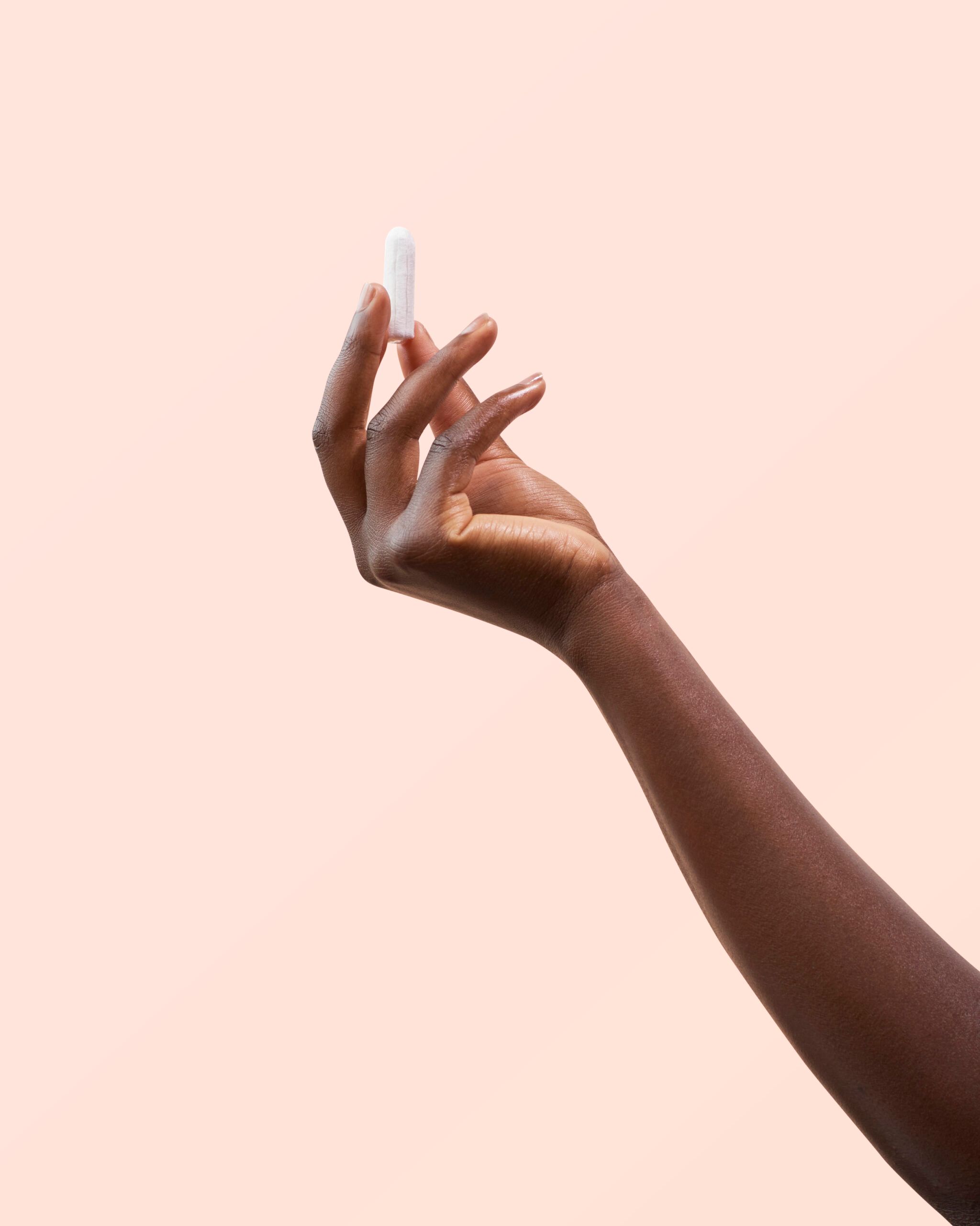 Une main tient un tampon blanc. Le tampon est de forme cylindrique.