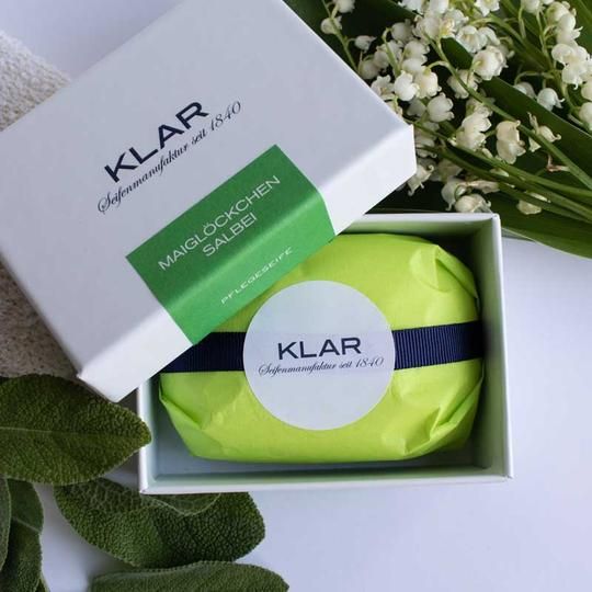 Open witte doos met groen verpakte zeep. Klar-logo en productnaam. Lelietje-van-dalen en salie.
