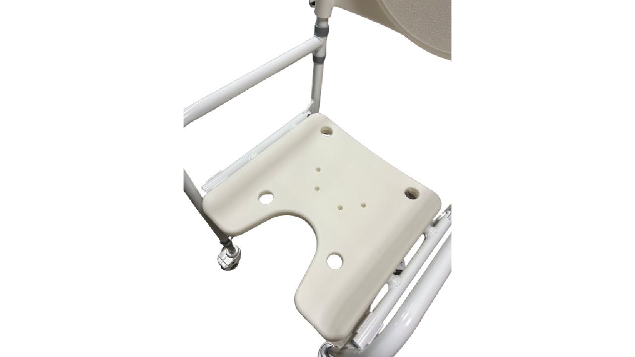 Gros plan sur l'assise d'une chaise de douche à roulettes. Beige, avec découpe et trous. Cadre et accoudoirs blancs.
