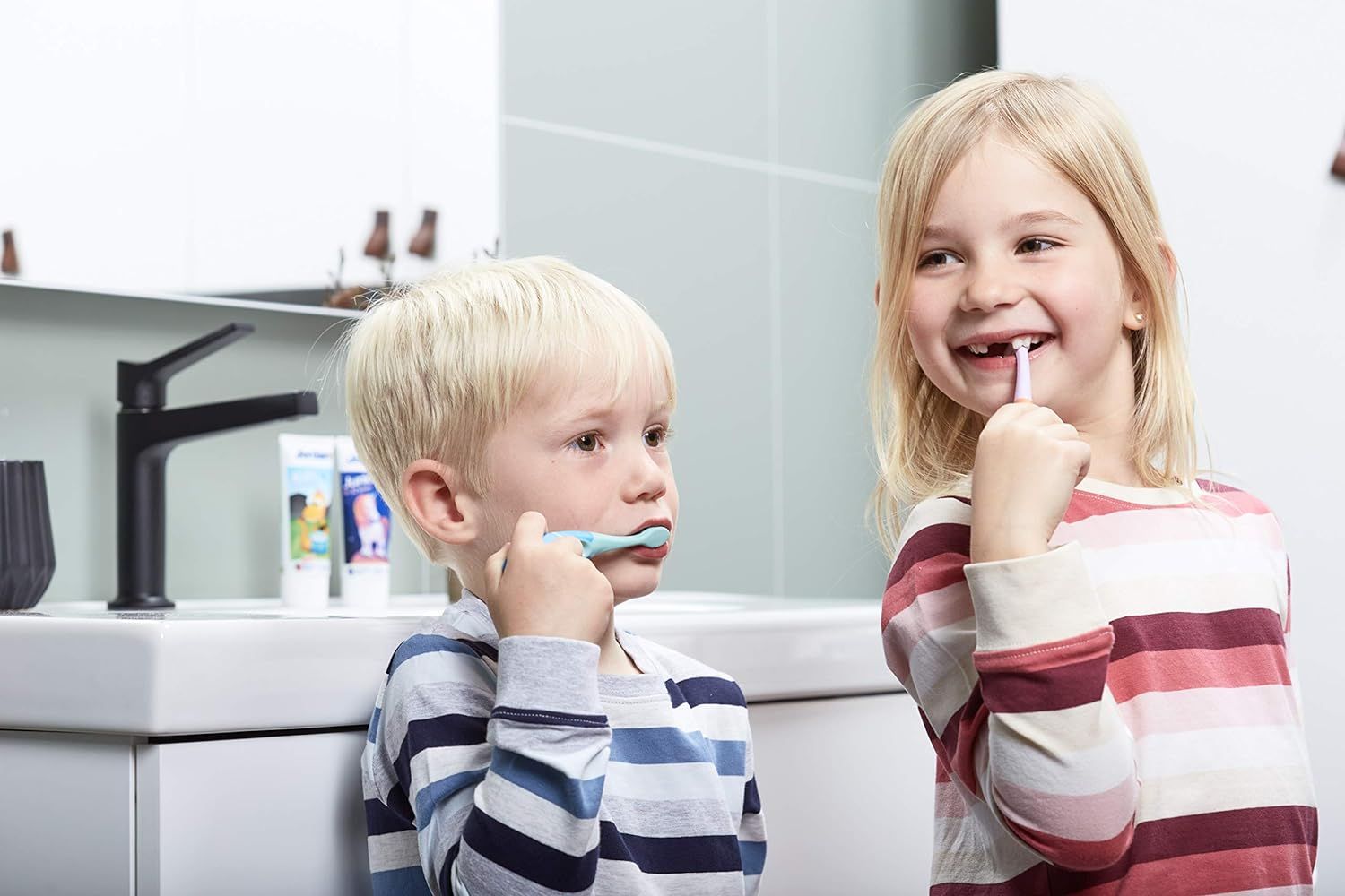 Deux enfants se brossent les dents dans la salle de bain.