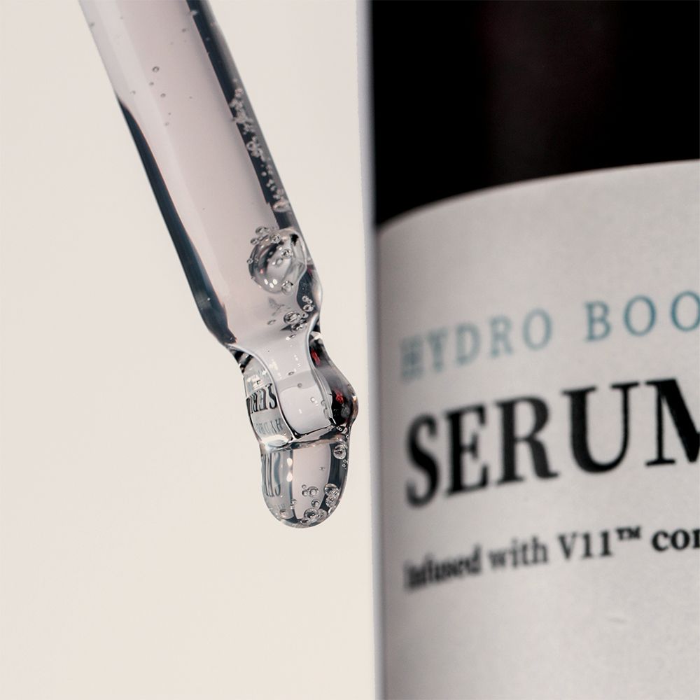 Close-up van een pipet met serum. Serum met luchtbellen. Fles met etiket op de achtergrond.