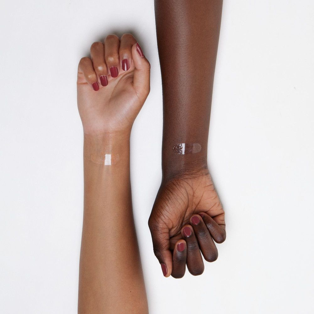 Twee armen met verschillende huidtinten. Op elke pols is een streep transparante lipgloss aangebracht.