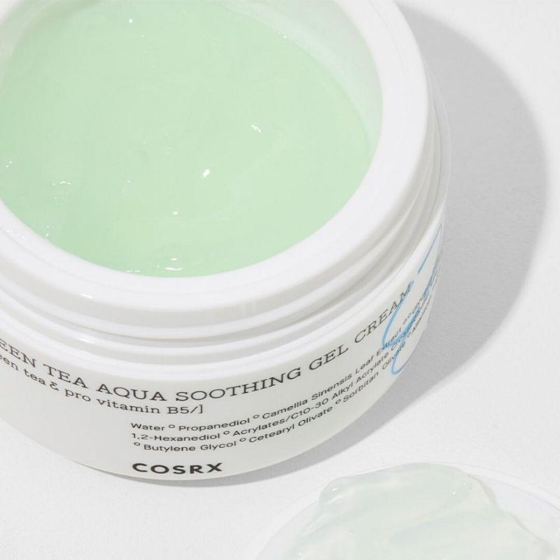 Close-up van de geopende pot. Groen-gelachtig product zichtbaar. Opschrift 'Green Tea Aqua Soothing Gel Cream' en 'COSRX'.