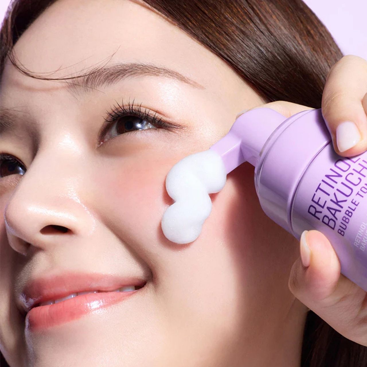Une femme applique le toner moussant Retinol Bakuchiol de SOME BY MI sur son visage.