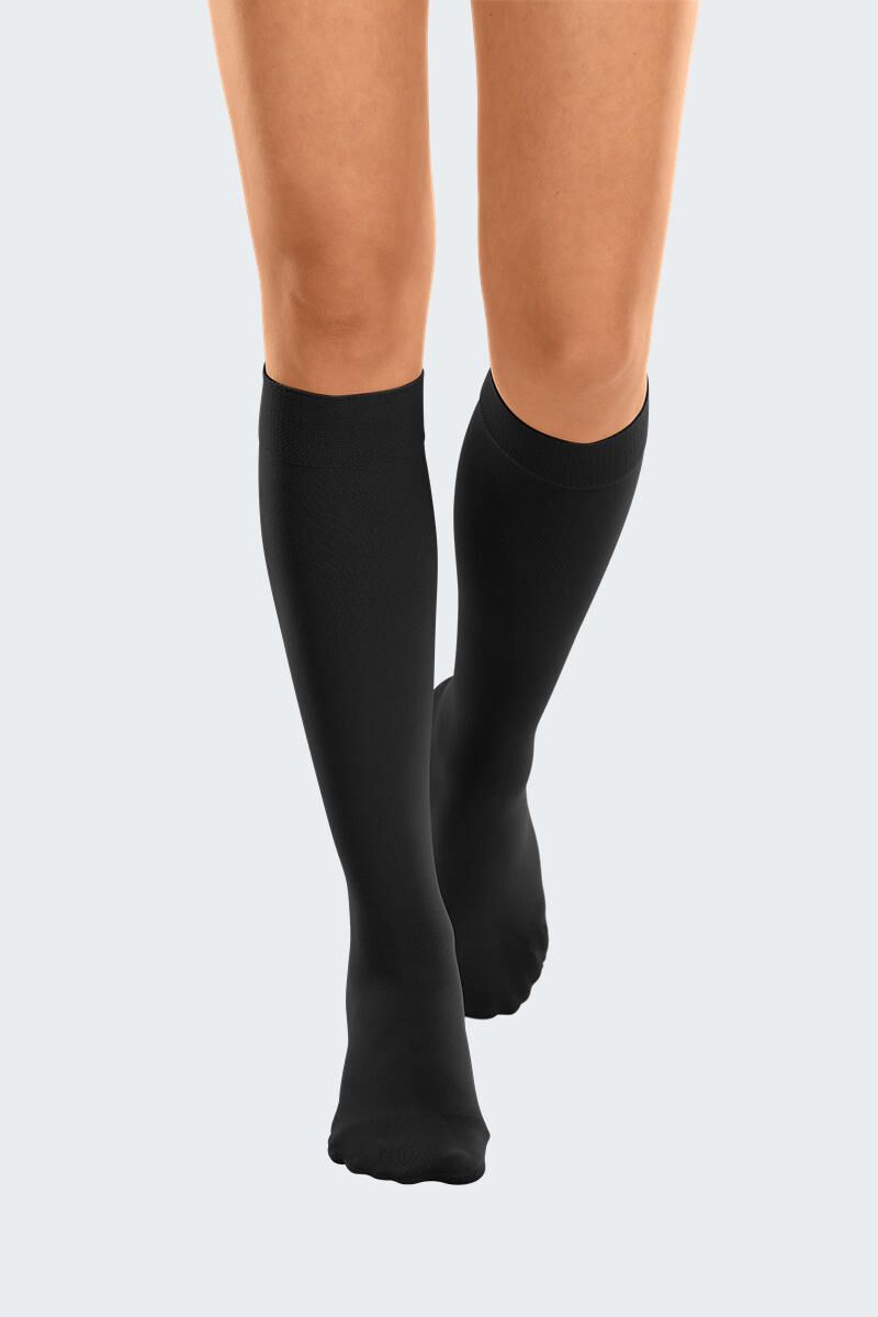 Bas de compression noirs sur les jambes. Bord en tricot. Vue de face.