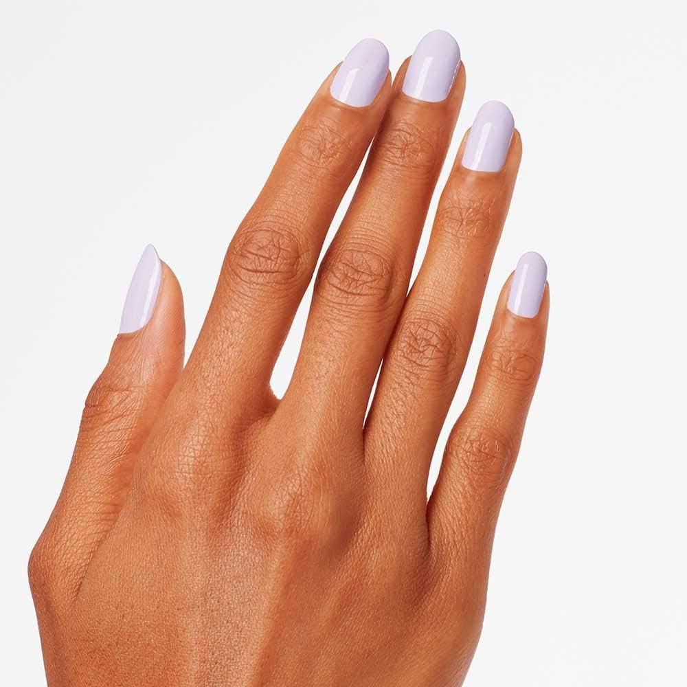 Main avec cinq ongles vernis en lilas clair. Les ongles sont de forme ovale.