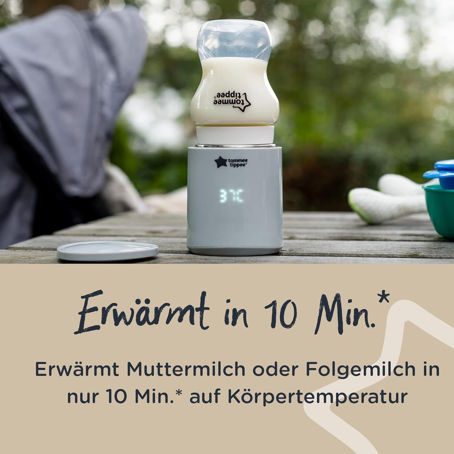 Chauffe-biberon portable avec biberon. Boîtier blanc, écran. Texte : Chauffe en 10 min. Logo Tommee Tippee.