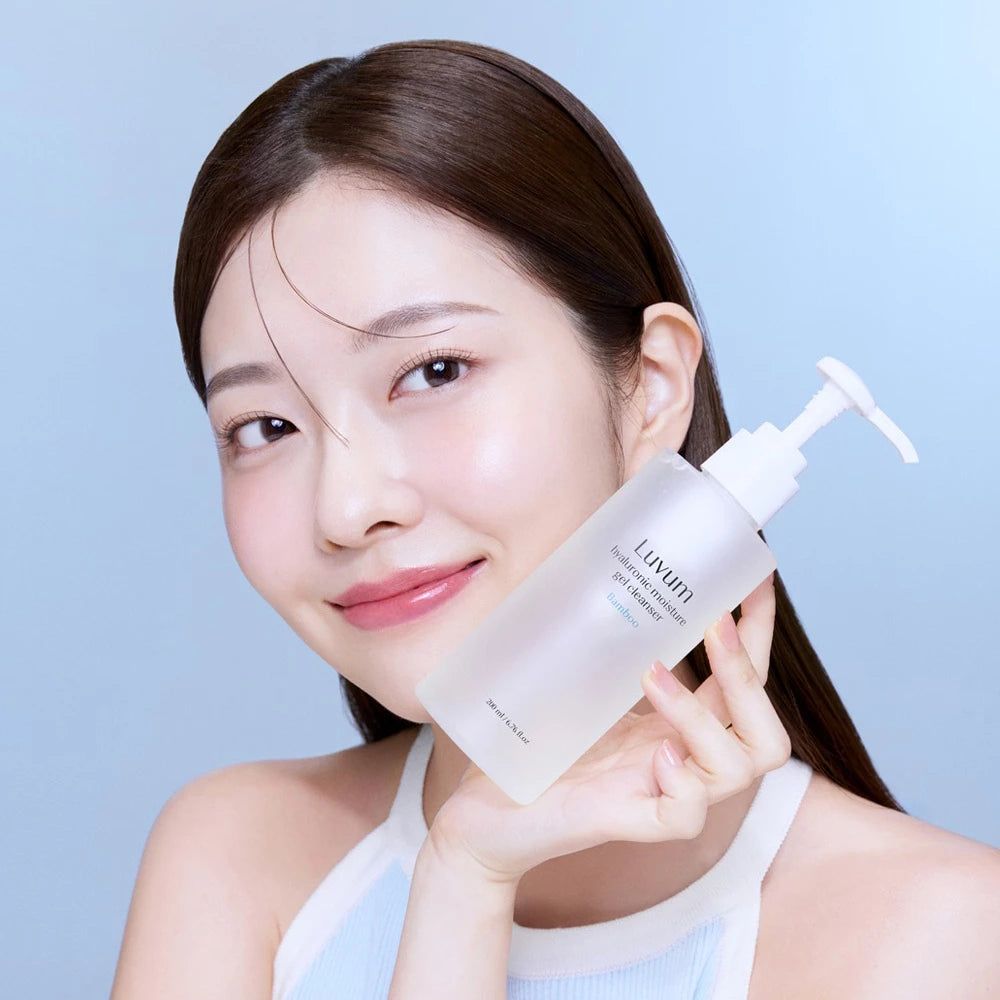 Vrouw houdt een transparante fles met witte pomp vast. Op de fles staat "Luvum Hyaluronic moisture gel cleanser".