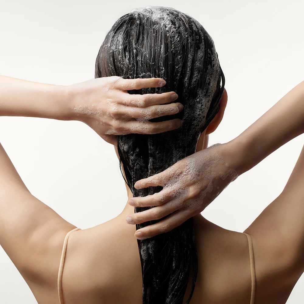 Personne se lave les cheveux avec du shampooing. Mains sur l'arrière de la tête. Cheveux couverts de mousse.