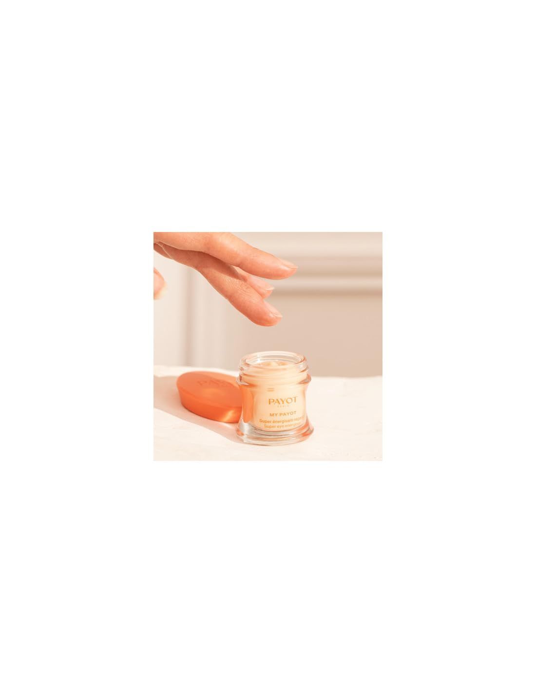 Pot en verre avec crème, à côté une éponge orange. Une main touche le pot.