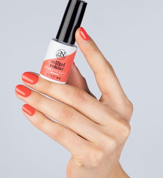 Hand met gelakte nagels en nagellakflesje. Flesje met opschrift "selfgel colour". Kleur nagellak: roze.