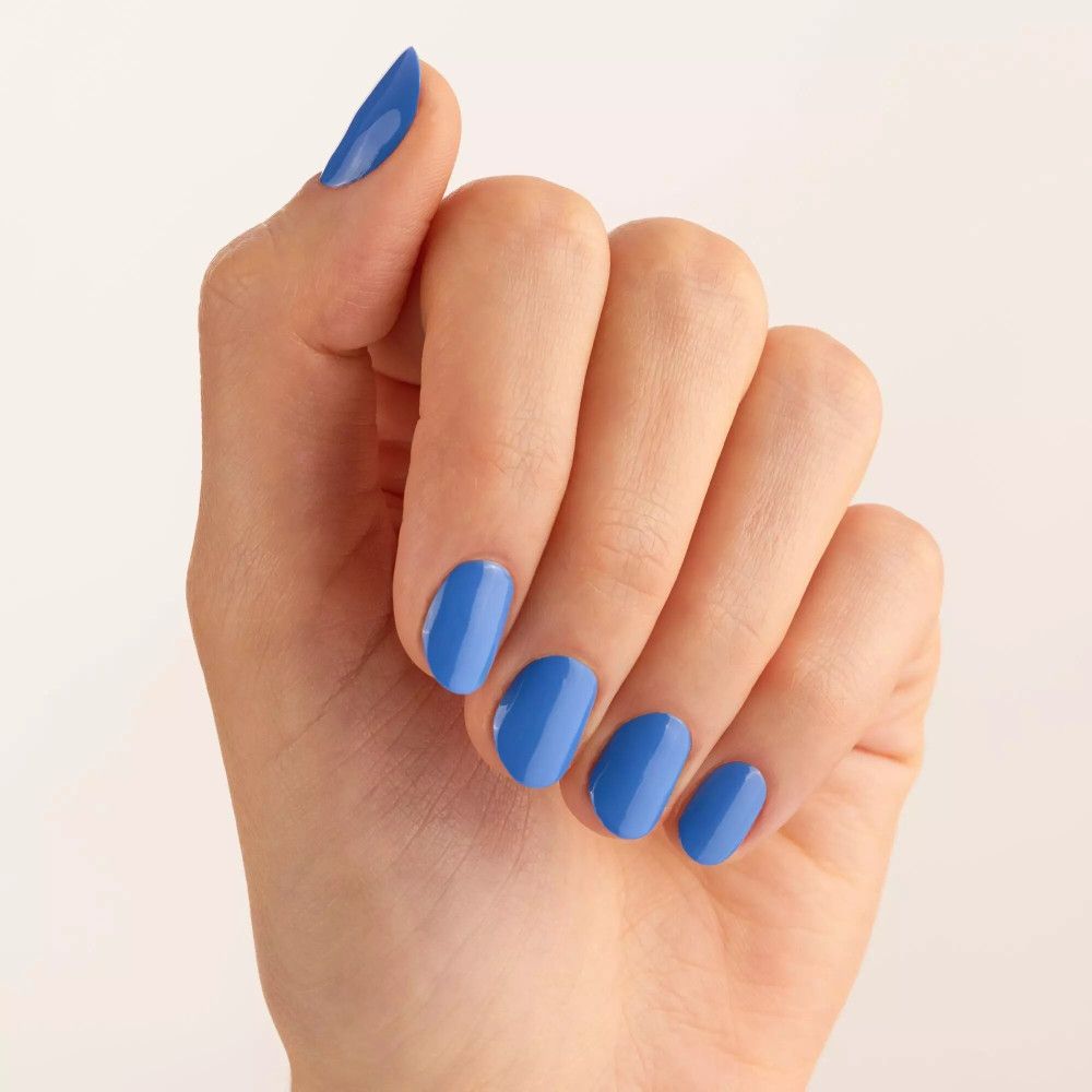 Main avec ongles vernis en bleu. Tous les ongles sont recouverts de vernis à ongles bleu.
