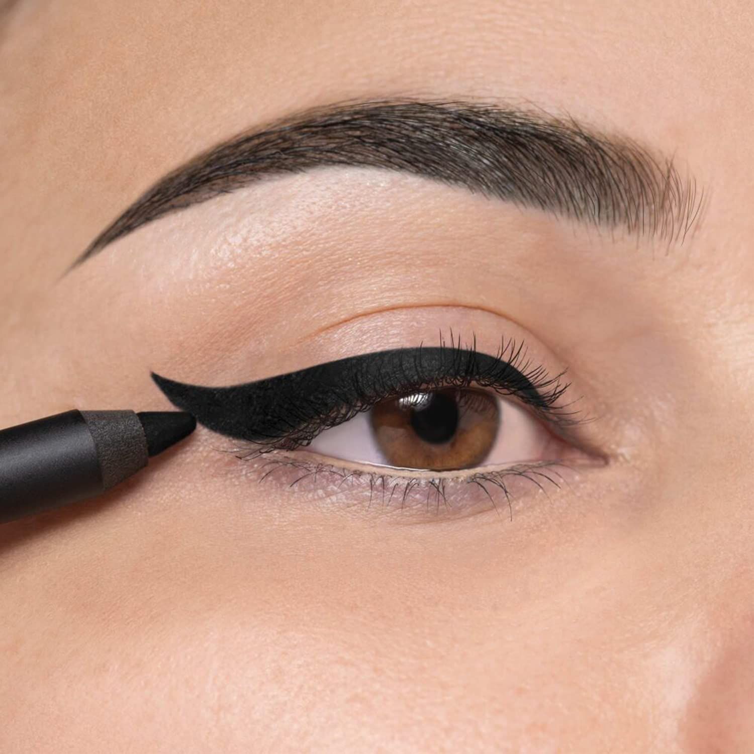 Oog met zwarte eyeliner. Oogpotlood in gebruik. Bruine ogen, donkere wenkbrauwen.