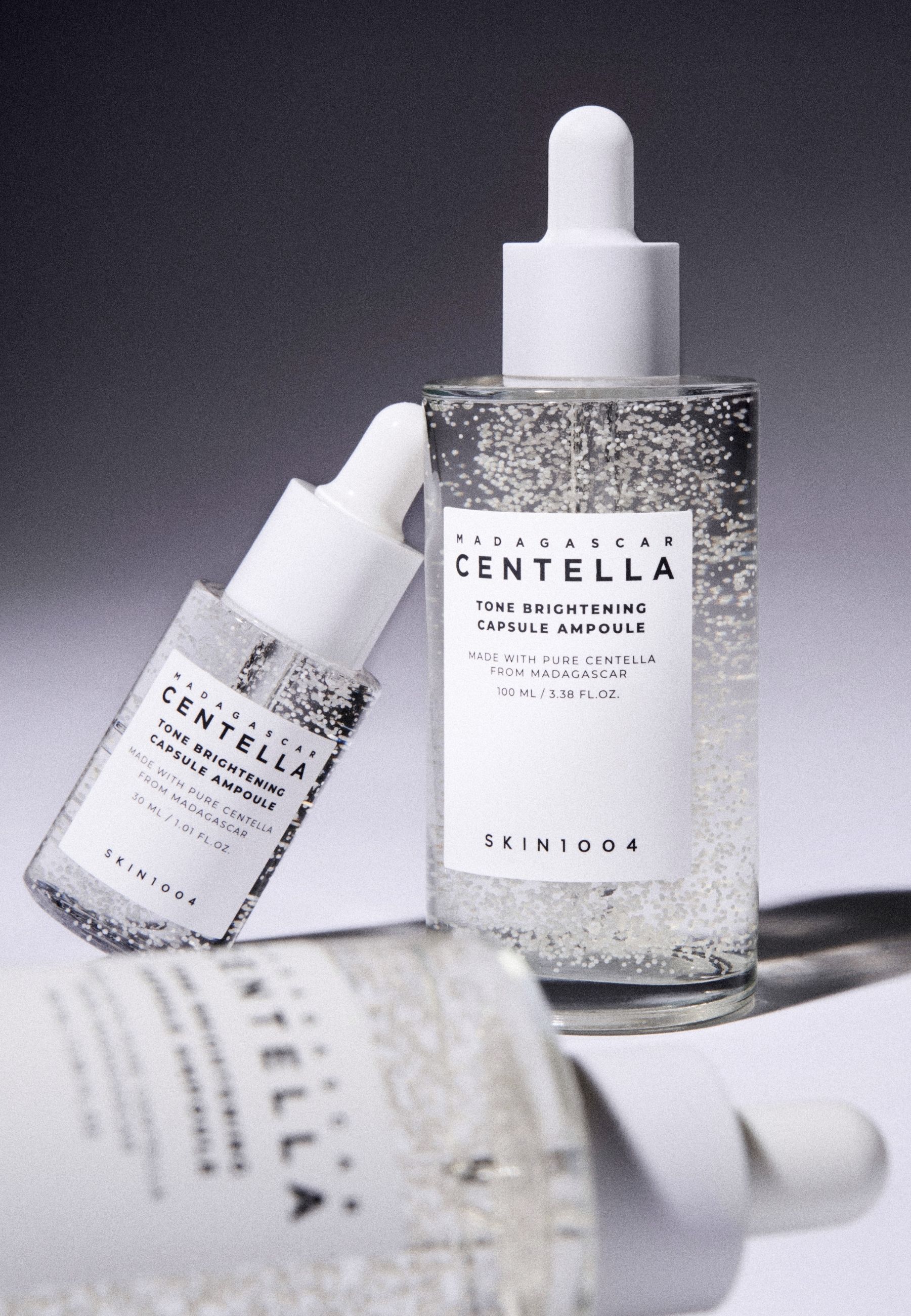 Deux flacons avec bouchon blanc et étiquette. Texte : MADAGASCAR CENTELLA, Tone Brightening Capsule Ampoule, SKIN1004.