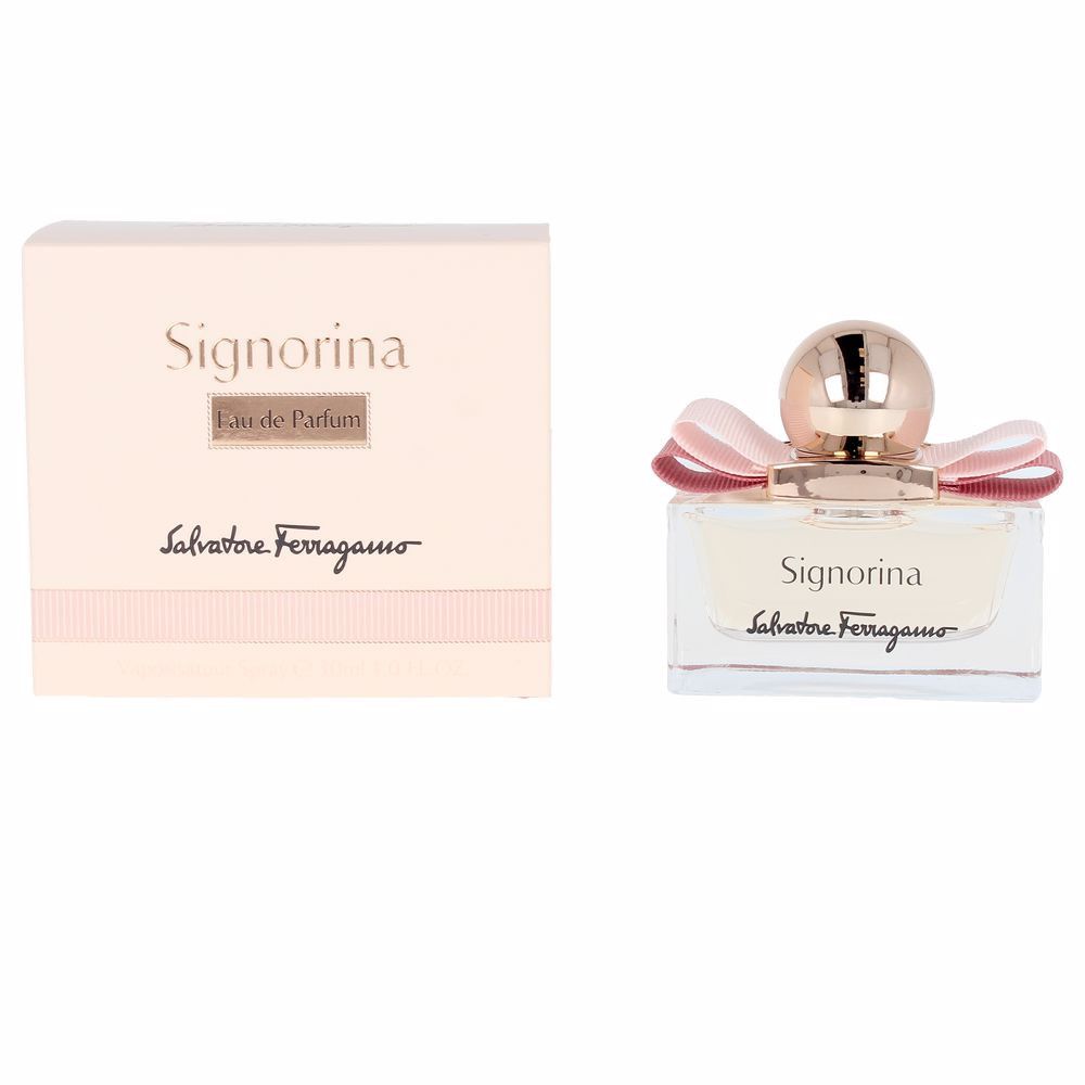 Signorina Eau de Parfum Spray. Rechthoekige glazen fles met roze vloeistof, roze strik en gouden dop. Verpakking ernaast.