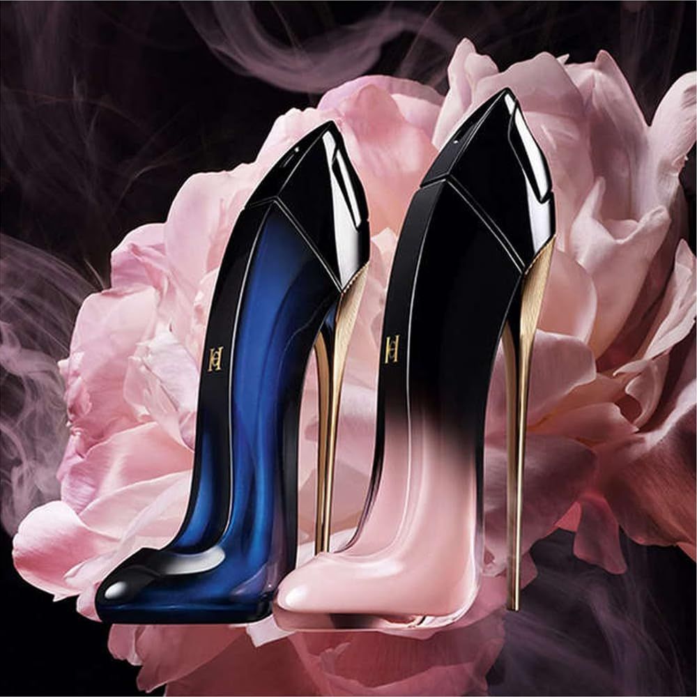 Deux flacons de parfum en forme de chaussure. Dégradé noir-rose et bleu-noir, talon doré. Devant des fleurs roses.