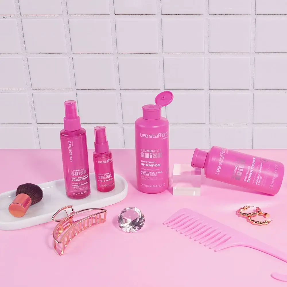 Diverse roze haarproducten op roze oppervlak. Inclusief: shampoo, conditioner, serum, borstel, kam.