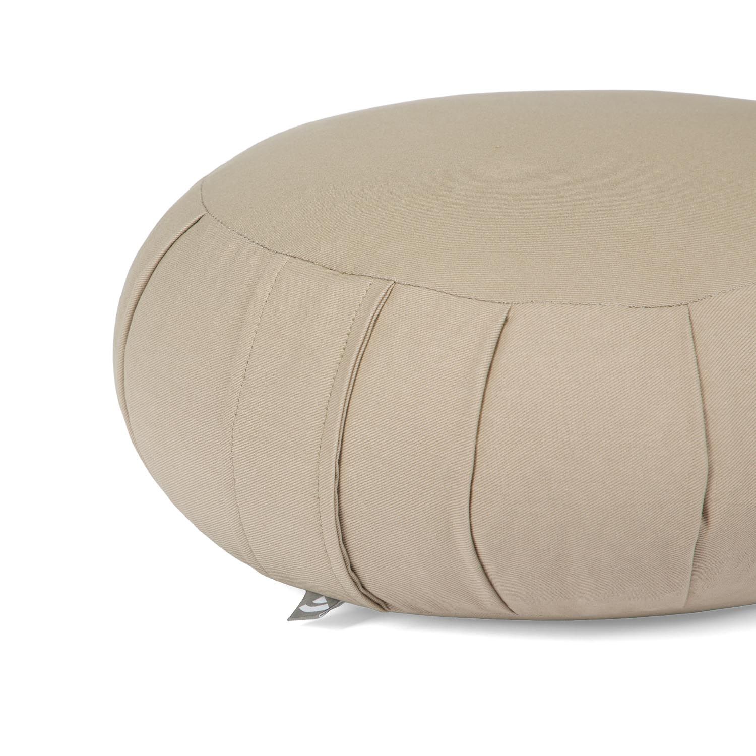 Gros plan sur un coussin de méditation ZAFU beige, rond, avec plis latéraux.