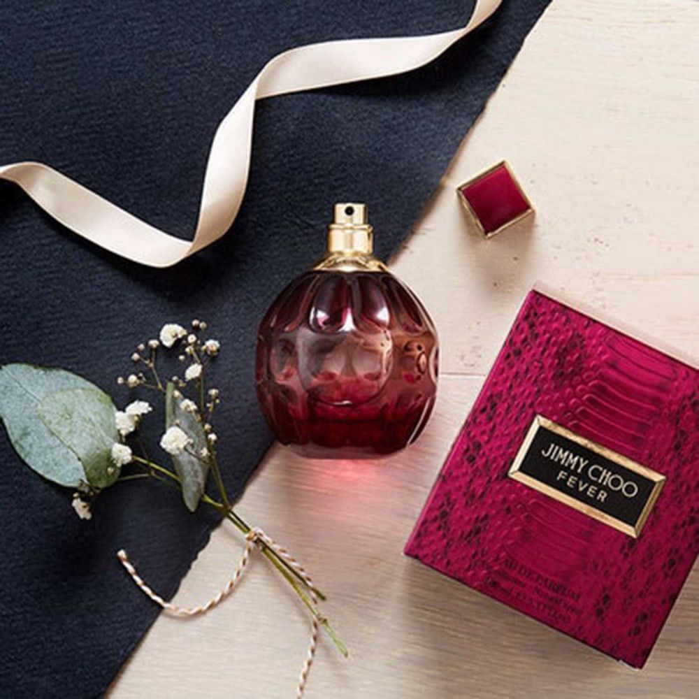 Flacon Jimmy Choo Fever Eau de Parfum, boîte, ruban et arrangement floral.