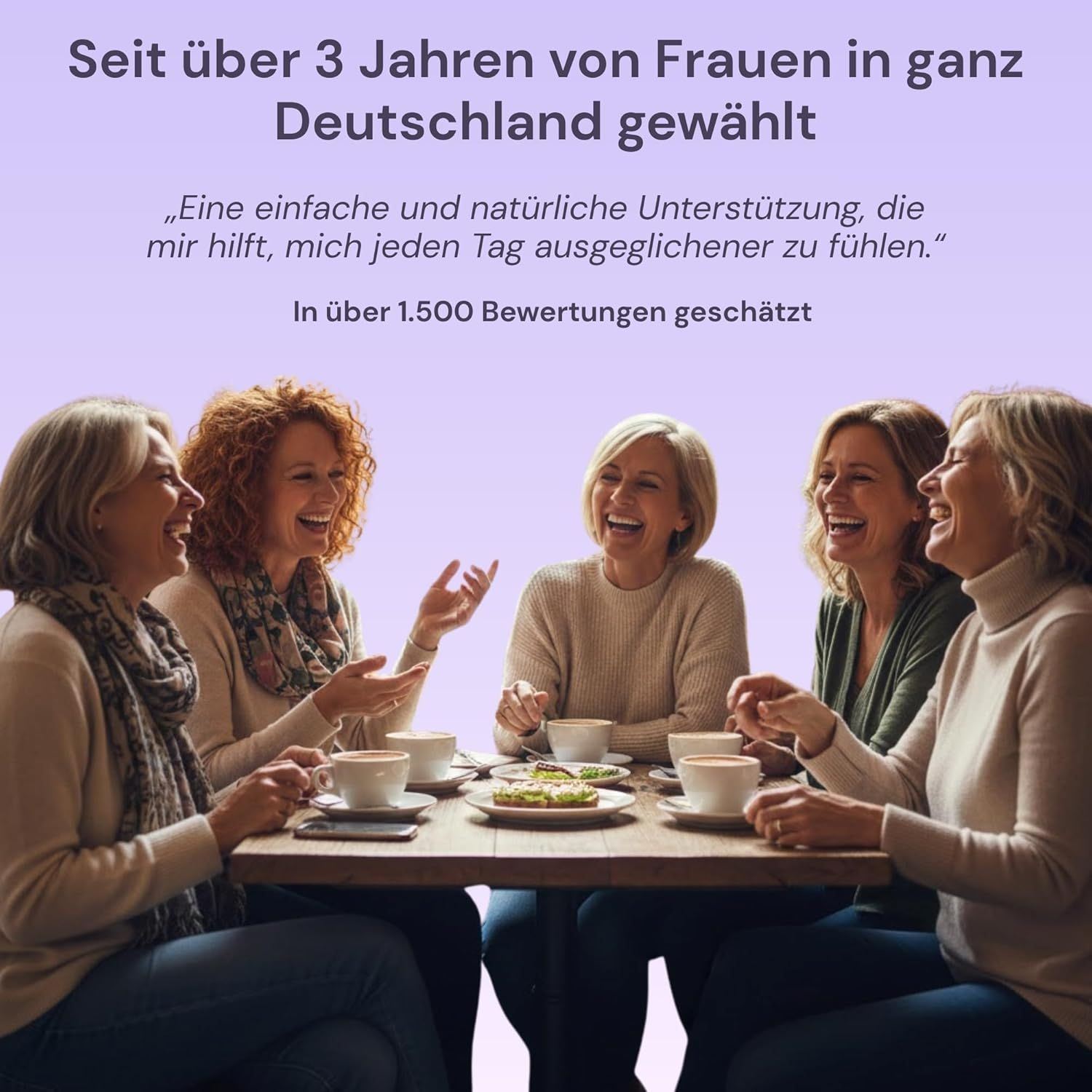 Cinq femmes riant d'âge moyen assises à une table.