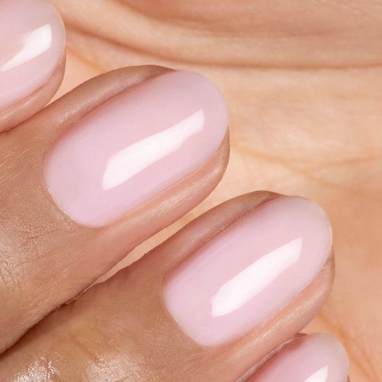 Gros plan sur des ongles vernis. Couleur rose clair. Forme arrondie. Finition brillante.
