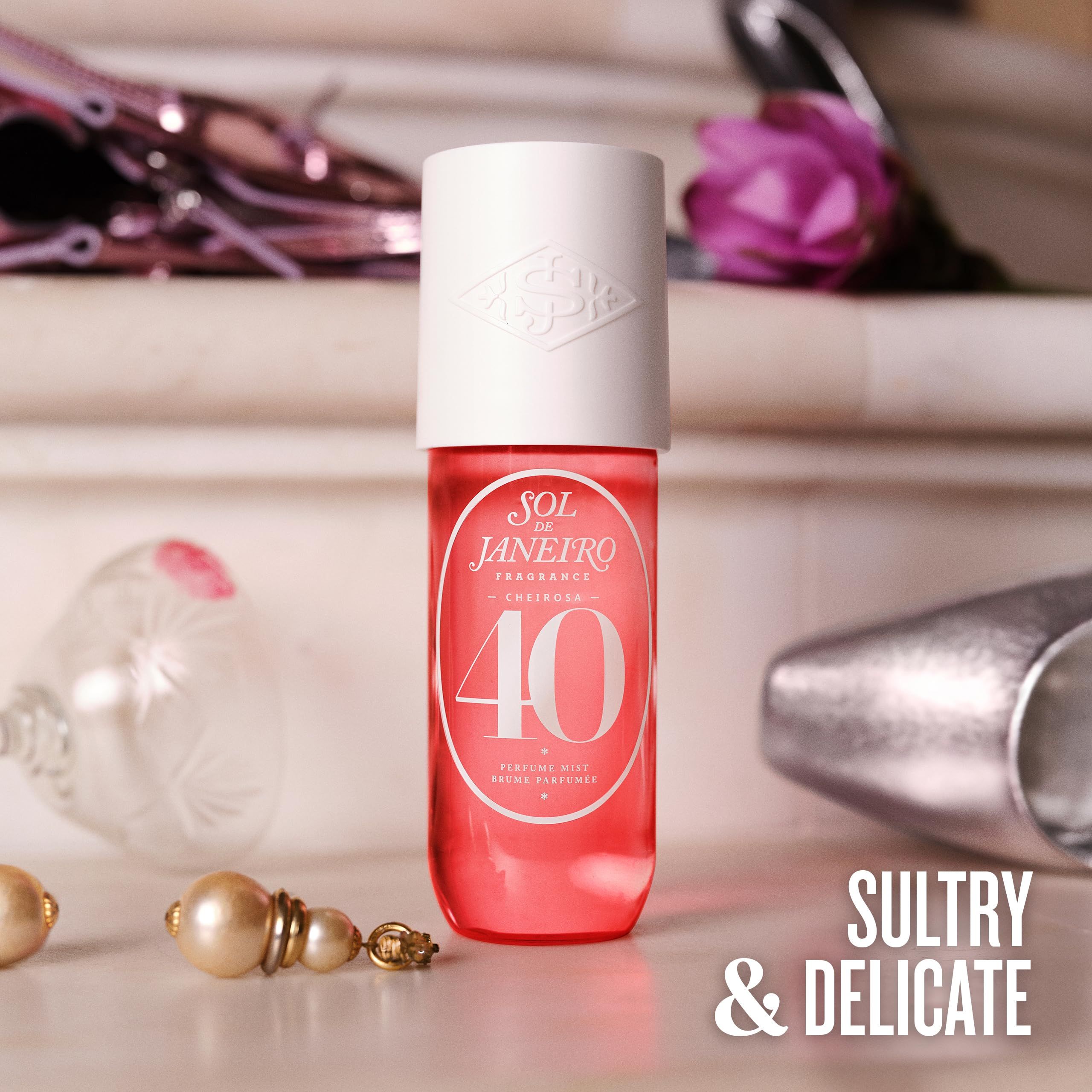 Rode fles met witte dop. Opschrift: Sol de Janeiro, Cheirosa '40, parfum spray. Achtergrond: sieraden, schoenen.