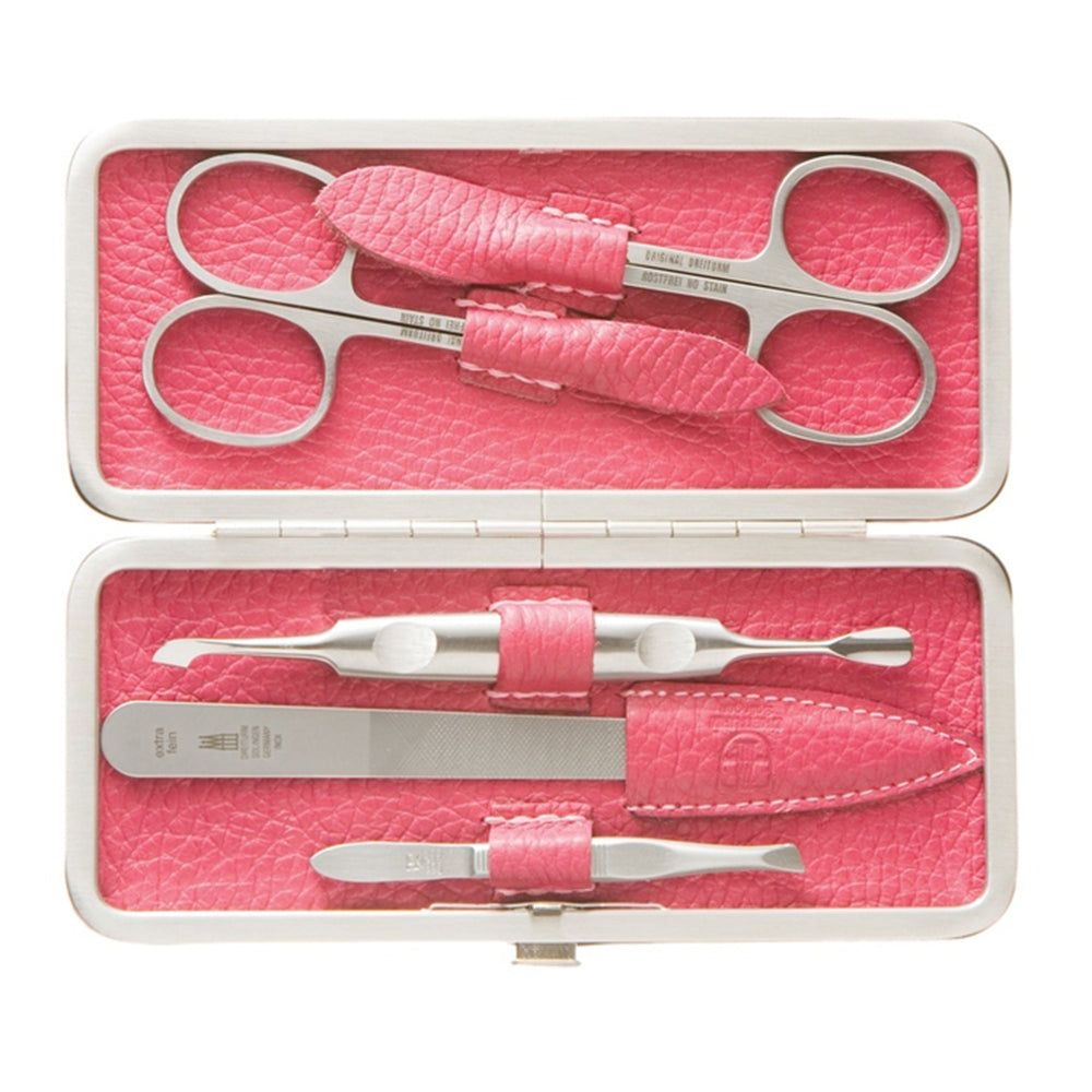 Trousse de manucure ouverte. Ciseaux à ongles, lime, repousse-cuticules, pince à épiler. Cuir rose, outils argentés.