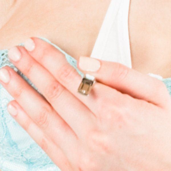 Lichte huid met lichtblauw BH-detail. Hand met ring.