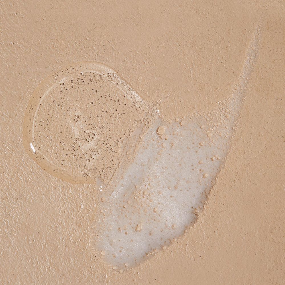 Uitgelopen douchegel met glitter op beige achtergrond. Een streep en een klodder.