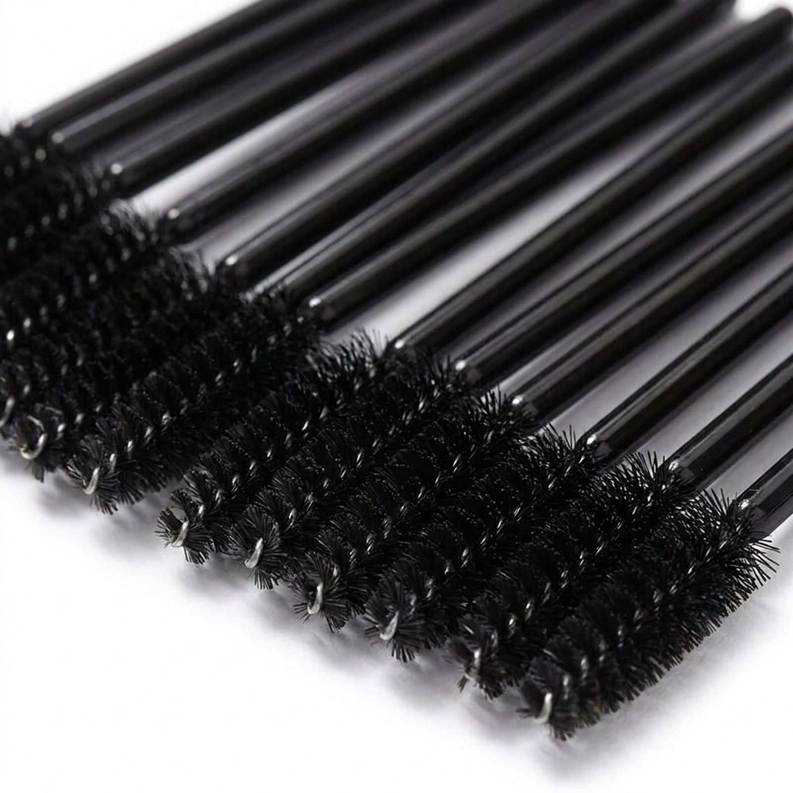 Gros plan des têtes de brosses à cils noires aux poils fins et anneaux métalliques.