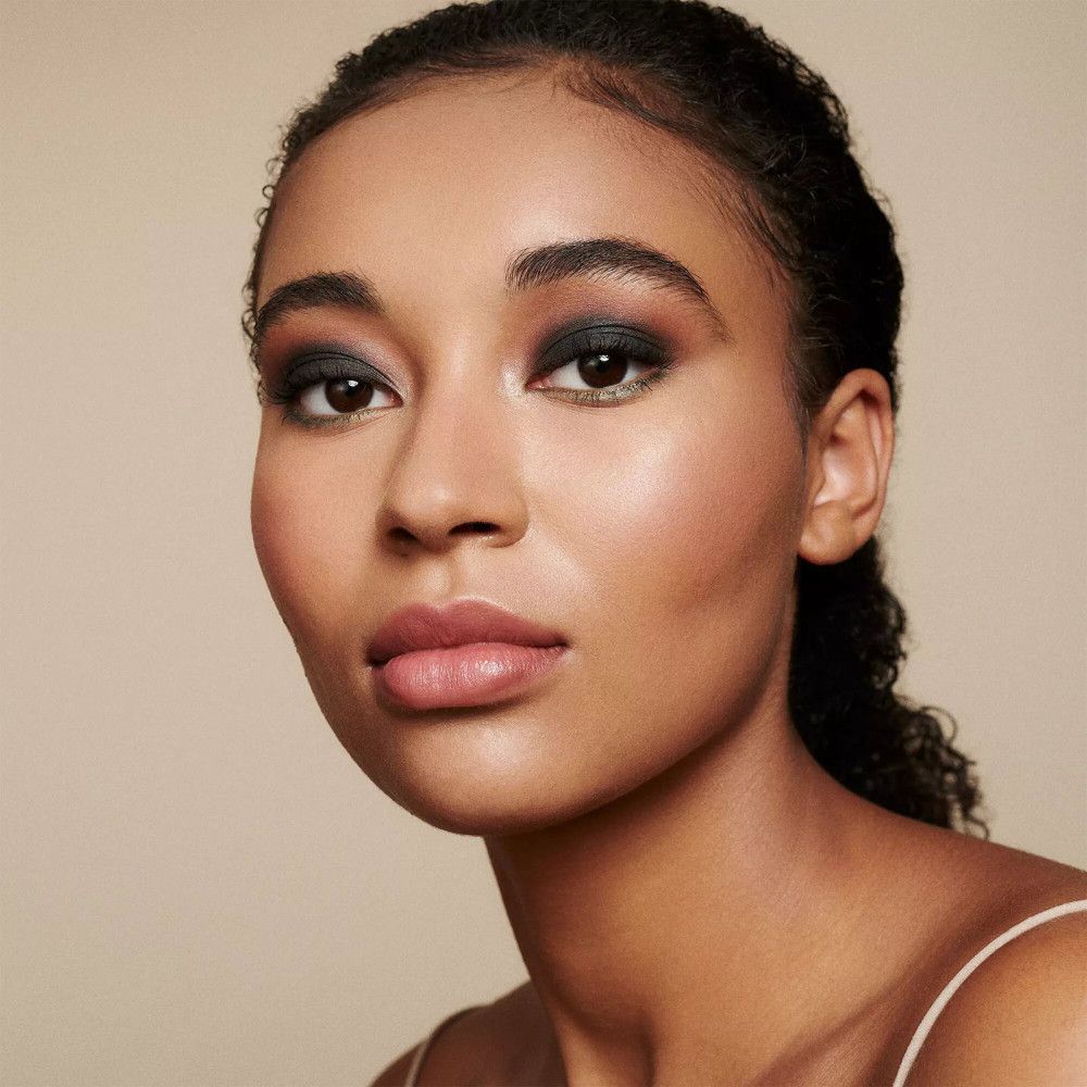 Portrait d'une femme maquillée. Yeux soulignés au crayon khôl. Fond sombre.