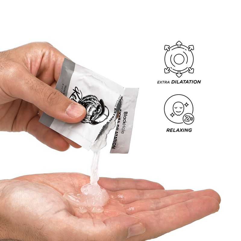 Hand opent sachet Black Hole Anal Extra Dilatation, glijmiddel wordt in handpalm gedeponeerd.
