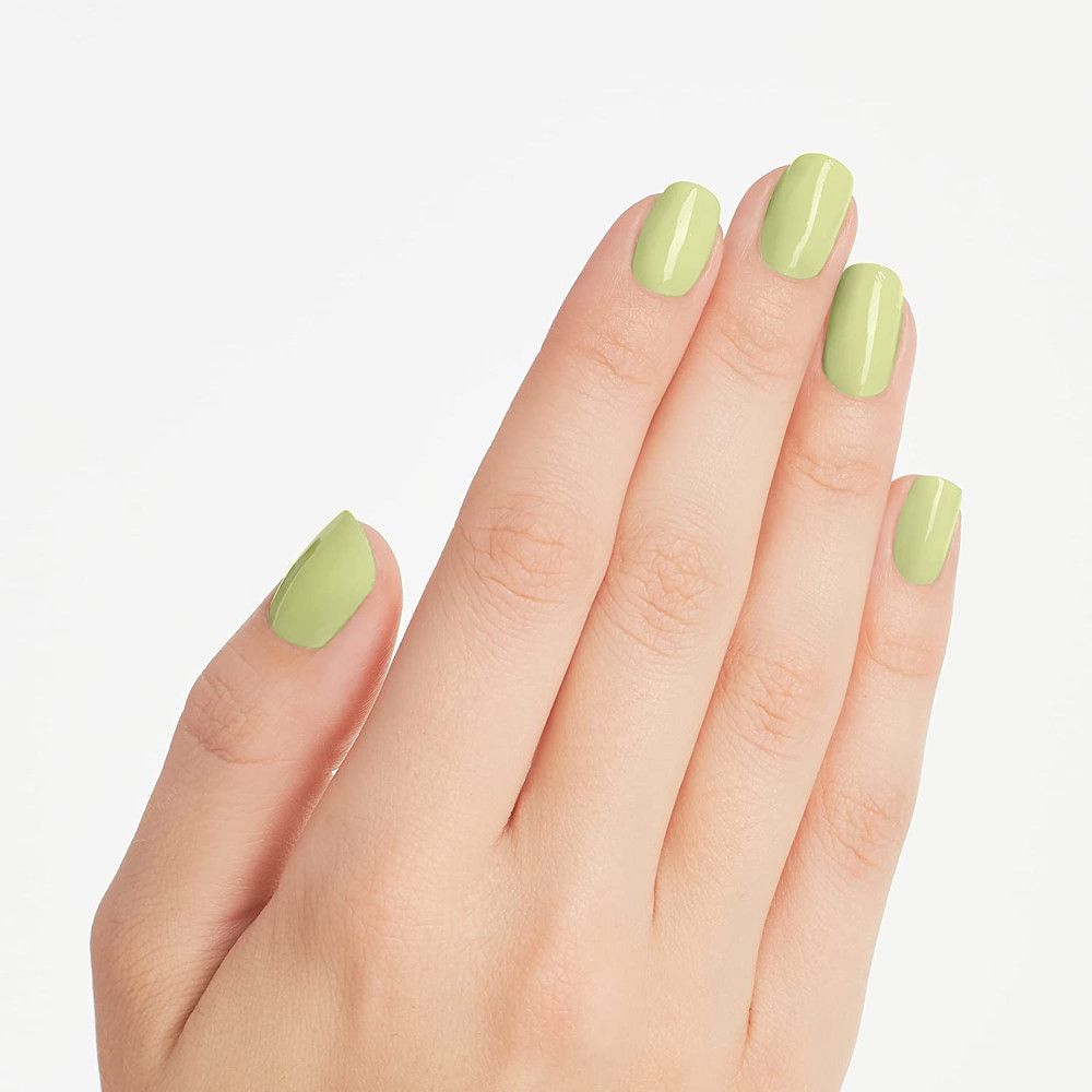 Main avec ongles peints en vert clair. Les ongles sont uniformément vernis et ont une surface brillante.