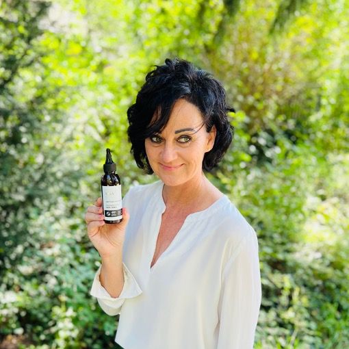 Femme tenant un flacon marron avec vaporisateur. Texte : Regenerating Hair Tonic.