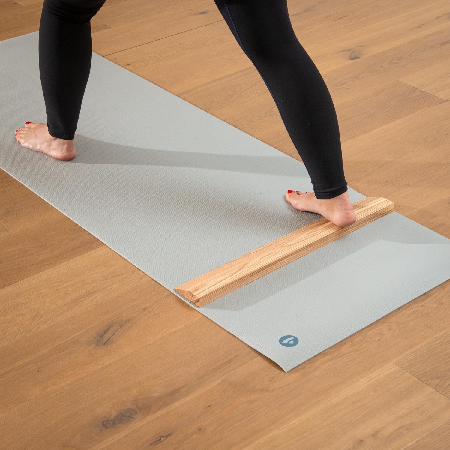 Persoon met handstandplank op yogamat. Lichtbruin hout. Grijze mat. Persoon in yoga-positie.